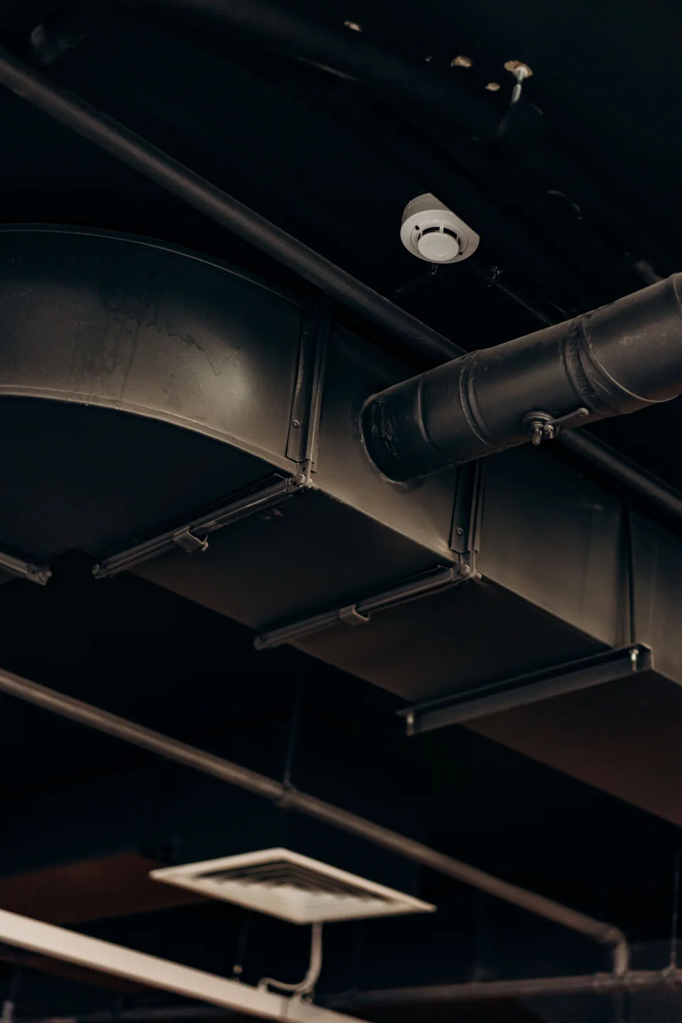 Exposed metal air ducts beneath a dark ceiling.