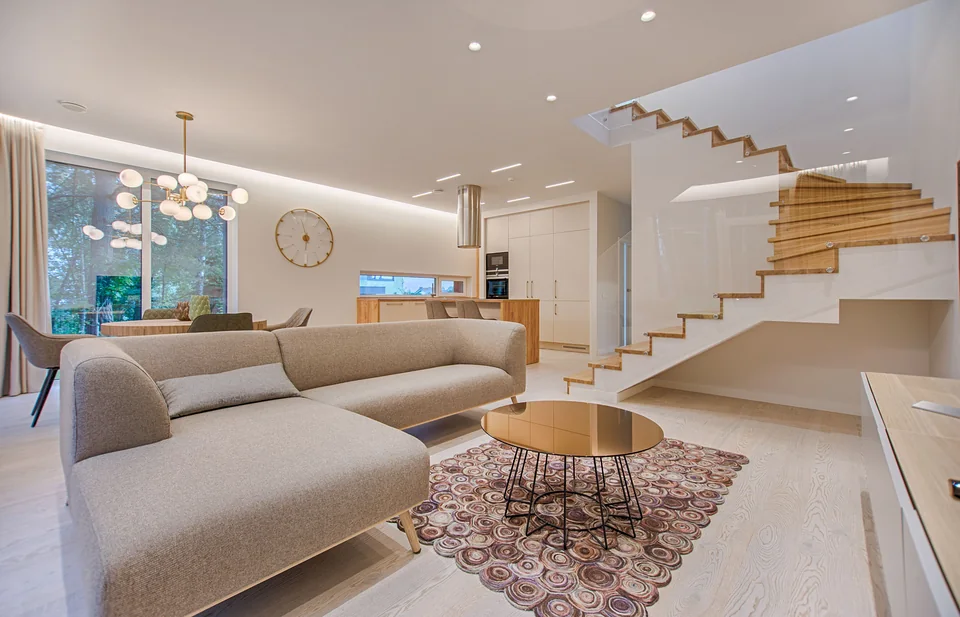Bright living room with a sofa, kitchen and wooden staircase.