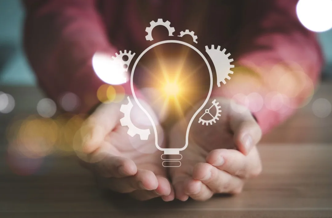 Hands holding a glowing lightbulb illustration.