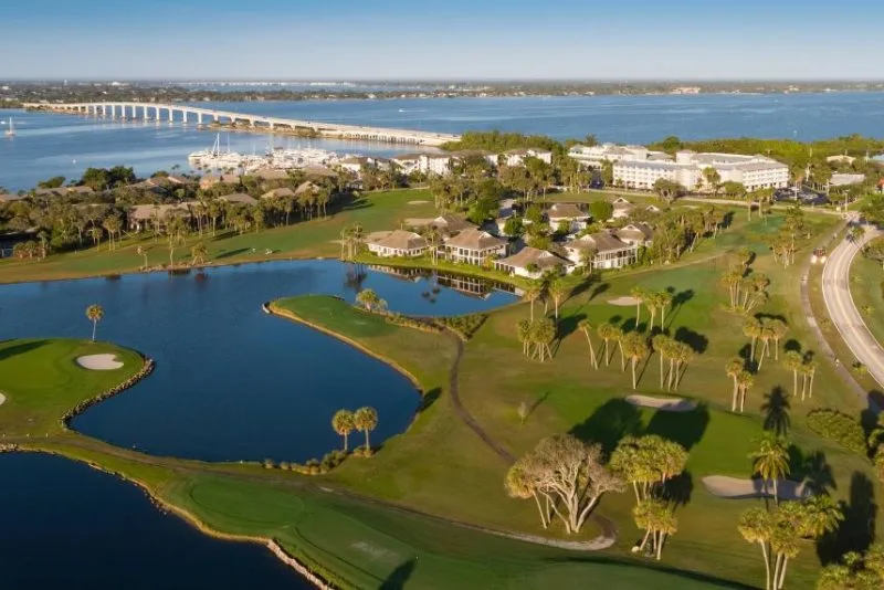 Aerial view of a golf course, waterway and bridge.