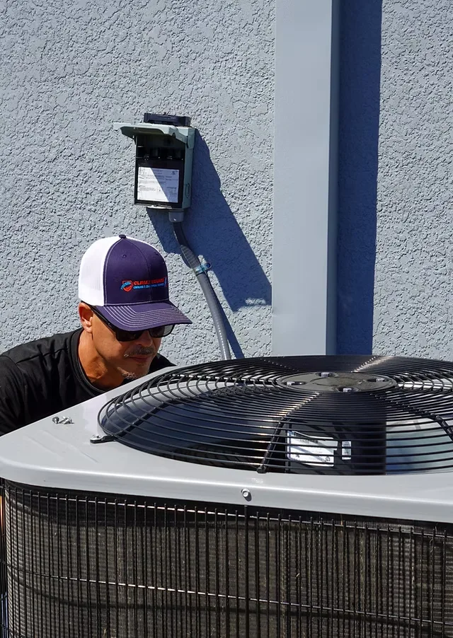 Technician inspecting the fan on an outdoor air conditioner.