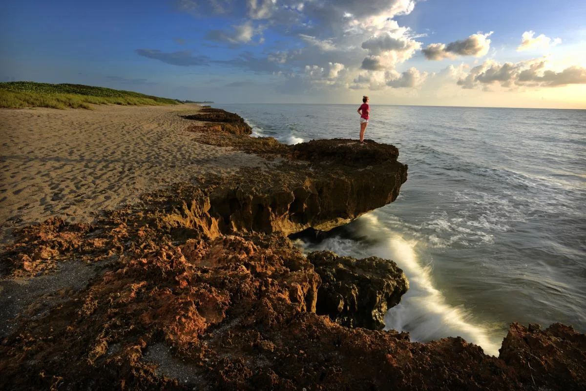 Rocky shoreline beside the ocean at sunset.