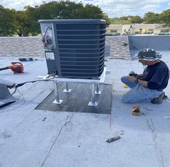 Technician beside an air conditioning unit on a flat roof.